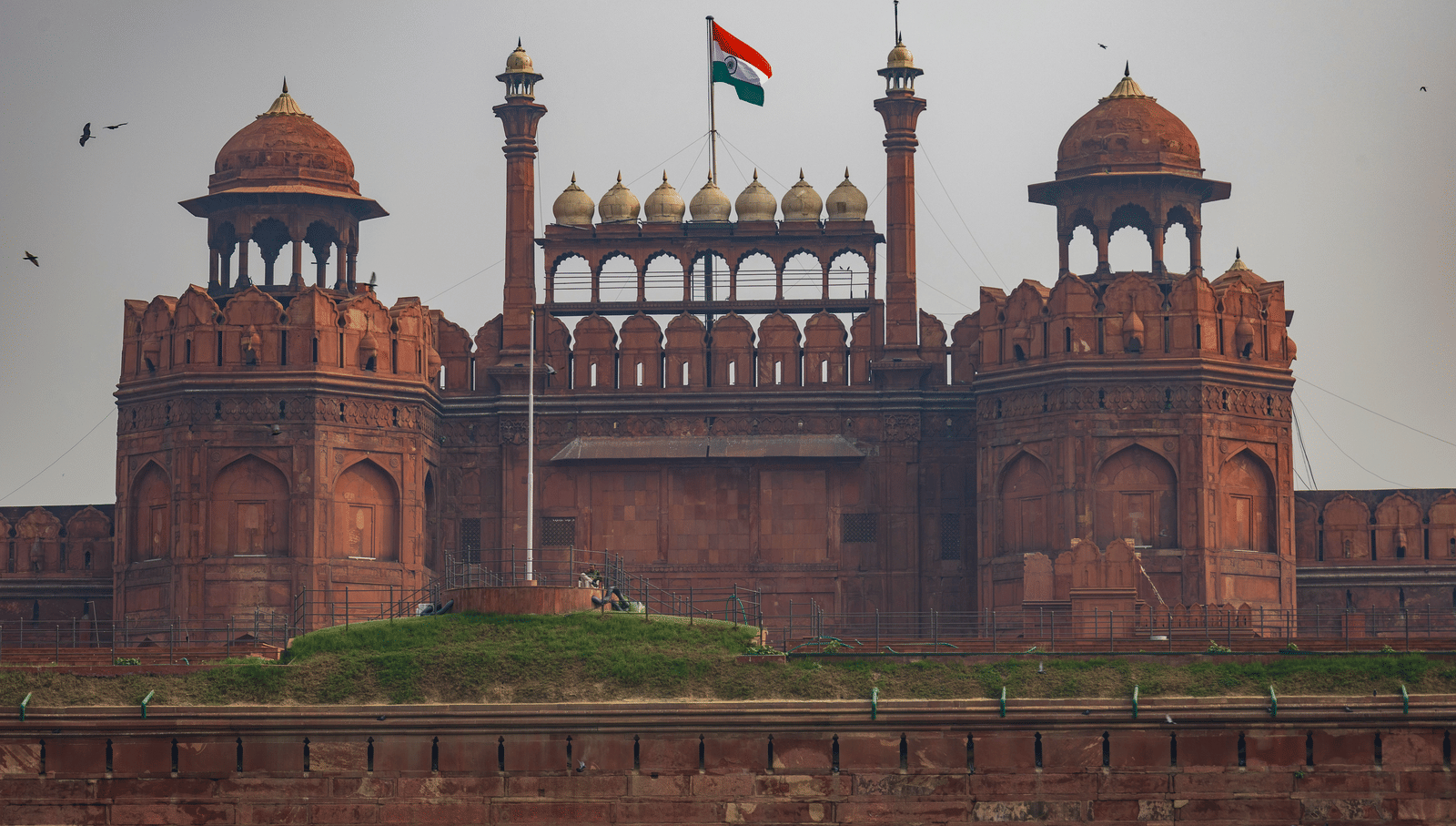 A front view of the Red Fort in Delhi with the Indian flag flying atop the central dome.